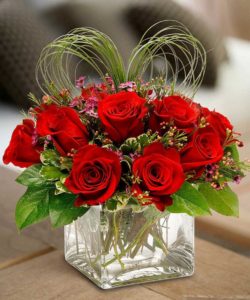 cute cube of a dozen red roses with an accent of a heart made of lily grass.
