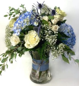 Express your feelings with this stunning array of blue and white flowers. Blue hydrangea, white roses, thistle and more are combined in an all around arrangement that is stunning from any angle.