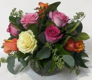 a lovely dozen roses in various hues is arranged into a bubble bowl